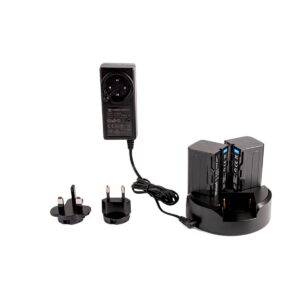 Hähnel_Trio_Charger_Sony_L-series-Kit_002 Hähnel Trio Charger Sony L-sarjan sarja sisältää mustan latausaseman, johon on asetettu kaksi akkua, virtalähteen ja kaksi alueellista pistokesovitinta, jotka on esitetty valkoisella pohjalla.