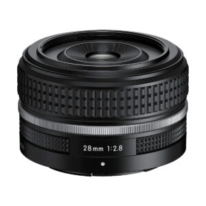 Nikon_Nikkor_Z_28mm_f_2_8_001 Nikon Nikkor Z 28mm f/2.8 SE -objektiivi on musta kameraobjektiivi, jossa on kuvioitu tarkennusrengas ja hopeinen korostus valkoista taustaa vasten.