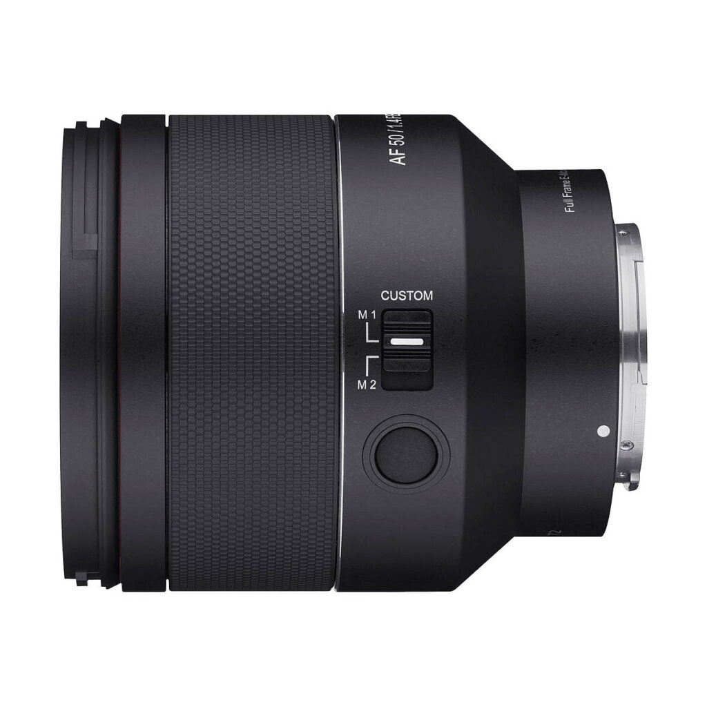 Samyang_AF_50mm_f_1_4_EF_II_002 A close-up side view of the Samyang AF 50mm f/1.4 II - Sony FE lens shows its black textured grip, M1/M2 switch, large button and metal mounting ring, all isolated against a white background.