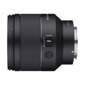 Samyang_AF_50mm_f_1_4_EF_II_002 A close-up side view of the Samyang AF 50mm f/1.4 II - Sony FE lens shows its black textured grip, M1/M2 switch, large button and metal mounting ring, all isolated against a white background.