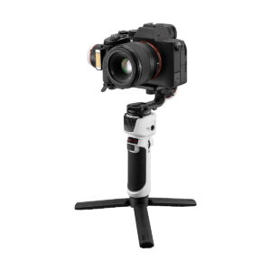 Zhiyun-Tech_Crane_M3_005 Zhiyun Crane M3 - Gimbaali on valkoinen käsikäyttöinen gimbal-stabilisaattori, jossa on musta kahva ja kokoontaitettavat jalustan jalat, kuvassa digitaalinen kamera asennettuna siihen valkoista taustaa vasten.