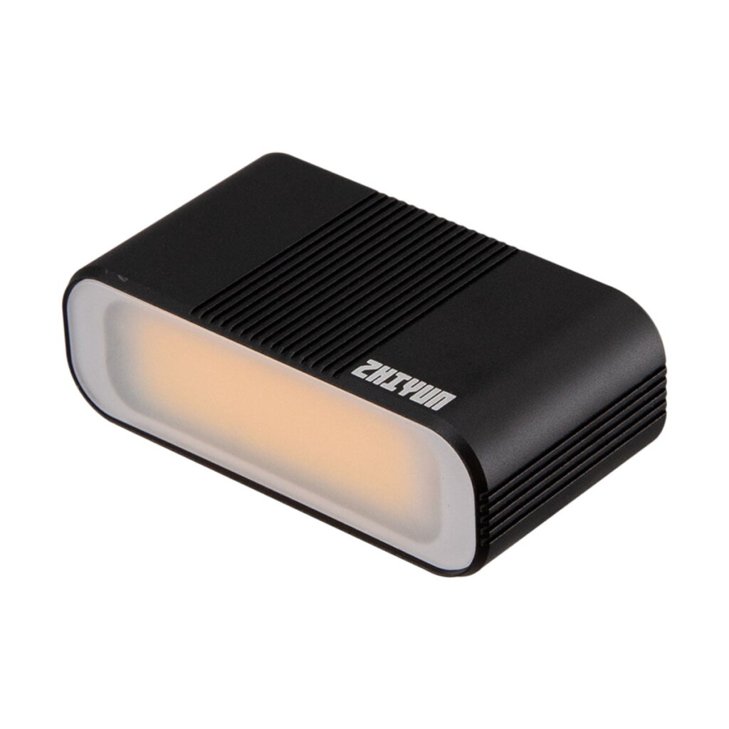Zhiyun_Smooth_5_006 Zhiyun Smooth 5 Combo älypuhelimille on kompakti, suorakaiteen muotoinen musta LED-valaisin, jossa on pyöristetyt reunat, lämpimän valon säteilevä himmeä etupaneeli, kuvioidut sivut ja ylhäällä näkyvä tuotenimi.
