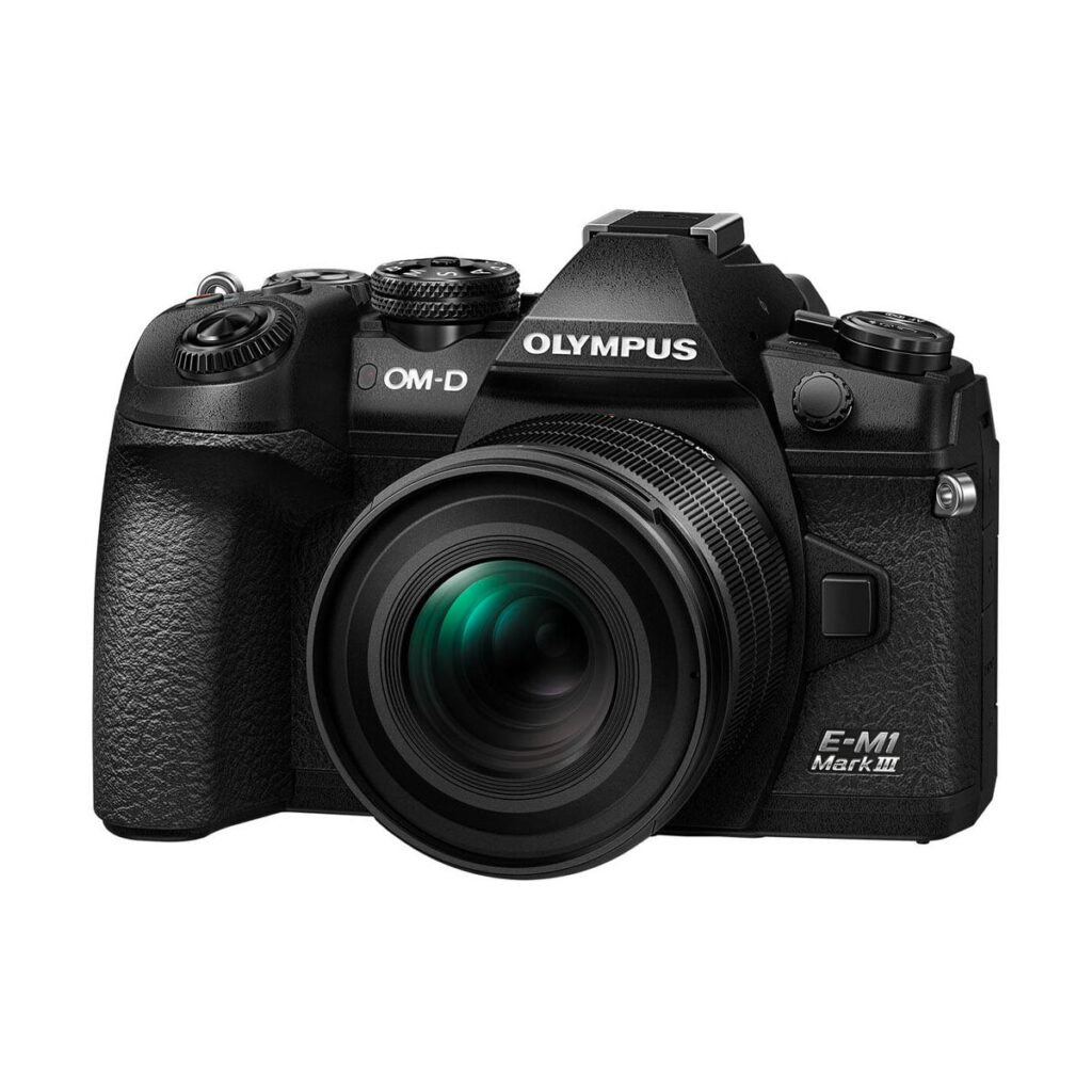 om_systems_20mm_f14_pro_03 OM SYSTEM M.Zuiko Digital ED 20mm f/1.4 PRO -objektiivi, joka on kuvattu edestä pienestä kulmasta, korostaa sen tyylikästä mustaa muotoilua, säätörenkaita ja yksityiskohtaista rakennuslaatua.