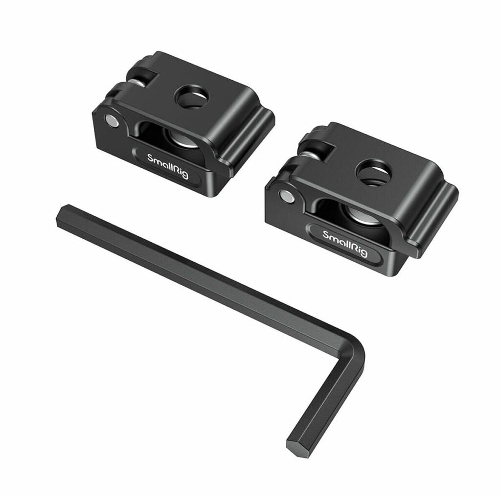 SmallRig_2418_Universal_Spring_Cable_Clamp_2_kpl_002 Kaksi mustaa SmallRig 2418 Universal Spring -jousikaapelikiinnikettä (2 kpl) näkyy mustan L-muotoisen kuusiokoloavaimen yläpuolella valkoisella pohjalla. Kummassakin puristimessa on keskireikä, urat ja siinä näkyy tuotemerkki.