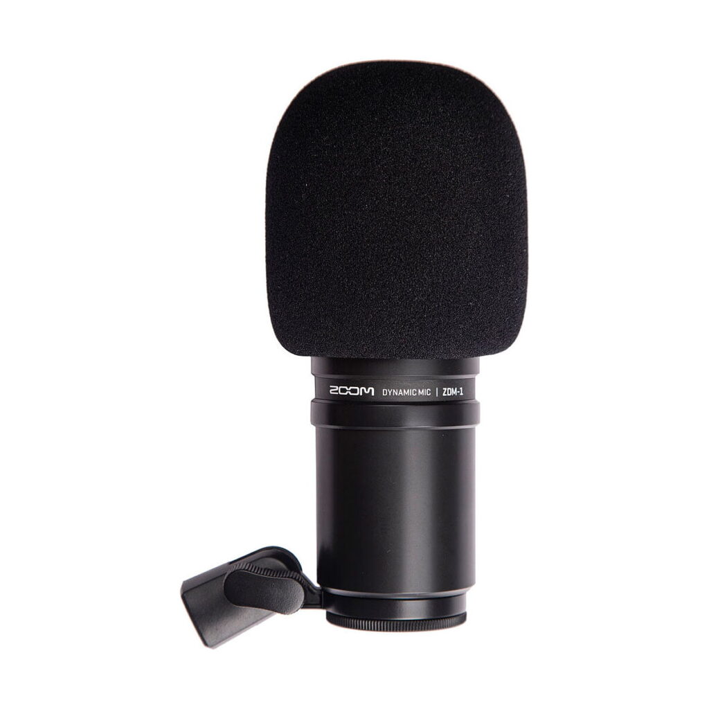 Zoom_ZDM-1_Podcast_Mic_Pack_004 Zoom ZDM-1 Podcast Mic Pack sisältää mustan dynaamisen mikrofonin, jossa on vaahtomuovinen tuulisuoja ja kiinnitysklipsi, pystyssä valkoista taustaa vasten.