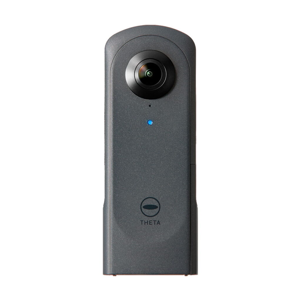 Ricoh_Theta_X_004 Musta Ricoh Theta X 360 asteen kamera, jossa on kalansilmäobjektiivi ylhäällä, sininen merkkivalo ja "THETA" painettu lähelle alareunaa, kuvattuna valkoisella pohjalla.