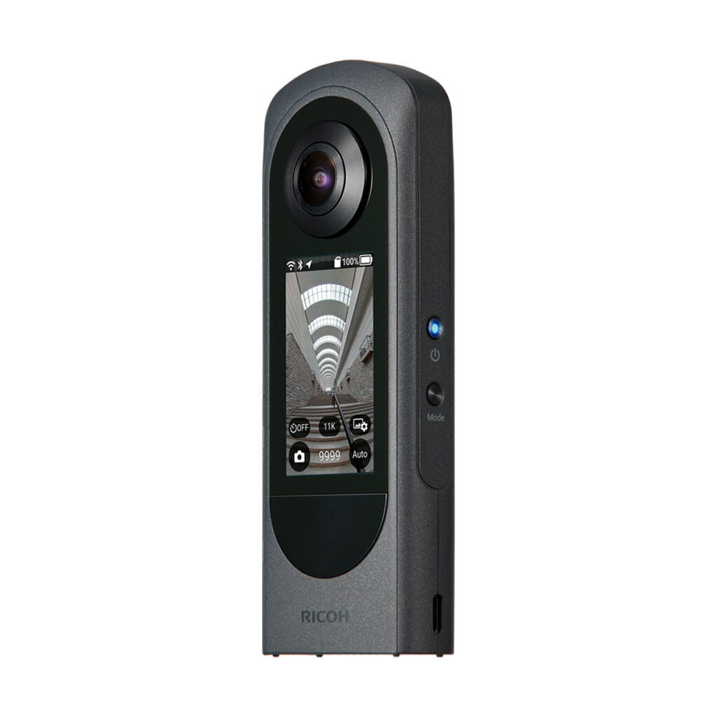 Ricoh_Theta_X_005 Ricoh Theta X on musta 360 asteen kamera, jossa on suuri yläobjektiivi, keskimmäinen värinäyttö, joka näyttää tunnelikuvaa, ja sivussa olevat ohjauspainikkeet.