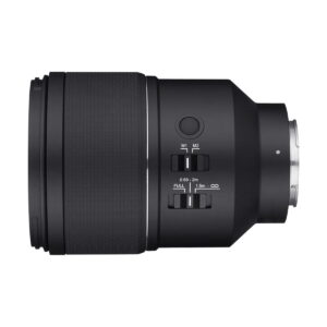 Samyang_AF_135mm_F_1_8_Sony-FE_003 Samyang AF 135mm F/1.8 - Sony FE -objektiivin sivukuva mustana, jossa on ohjauskytkimet, painikkeet, kuvioitu tarkennusrengas ja metallinen objektiivin kiinnike oikealla, valkoista taustaa vasten.