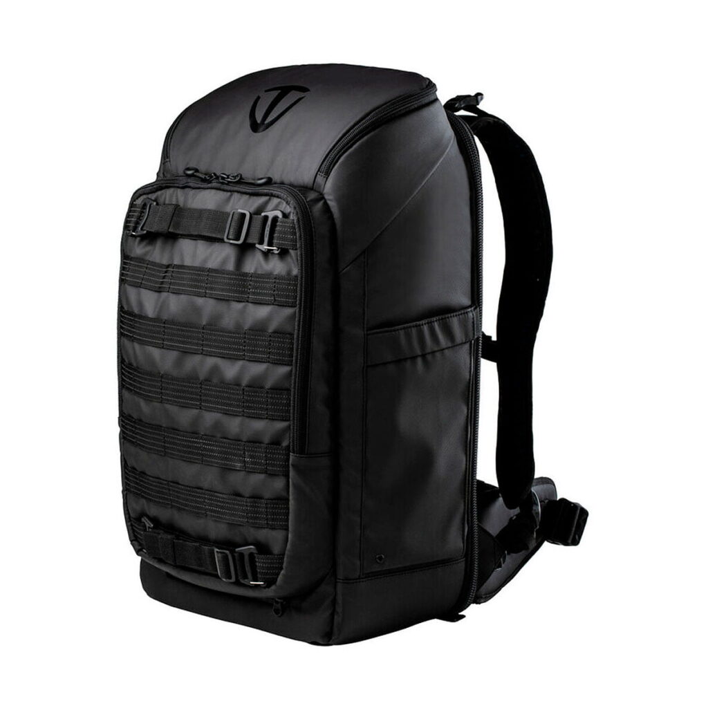 Tenba_Axis_32L_Tactical_Backpack_001 Tenba Axis 32L taktinen reppu, jossa on kova kuori, useita etuhihnoja ja solkia, pehmustetut olkahihnat ja lantiovyö, on esitetty tyylikkään mustana valkoista taustaa vasten.