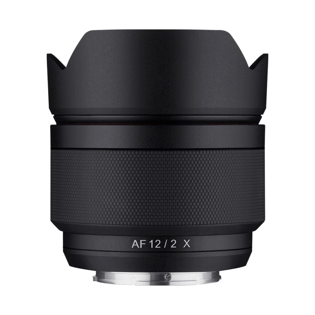 Samyang_AF_12mm_Fuji_X_001 Samyang AF 12mm f/2 -objektiivi Fuji X:lle, jossa on musta, kuvioitu kahva, terälehden muotoinen huppu ja metallinen kiinnitysjalusta. "AF 12/2 X" on merkitty etupuolelle. Objektiivi on kuvattu tavallista valkoista taustaa vasten.