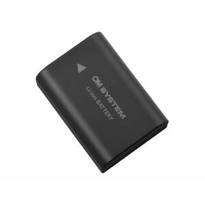 Musta OM SYSTEM BLX-1 akku litiumioniakku, jonka pinnalla on valkoinen nuoli ja teksti "Li-ion BATTERY", valkoista taustaa vasten.
