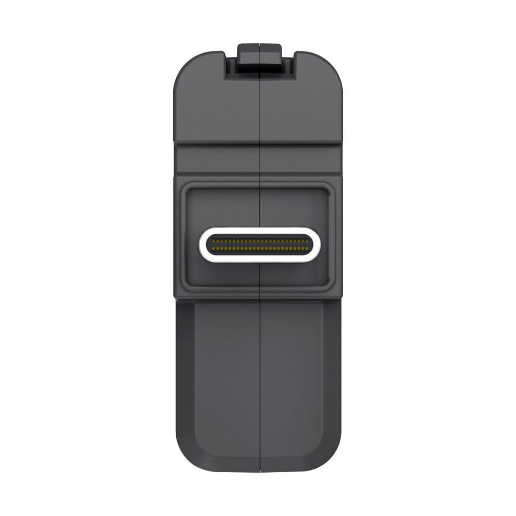 Insta360_One_X2_3_5mm_Mic_Adapter_with_Charging_Input_004 Lähikuva Insta360 One X2 3,5 mm:n mikrofonisovittimesta, jossa on harmaa suorakulmainen aukko ja useita kultaisia nastoja, pystysuorassa valkoista taustaa vasten.