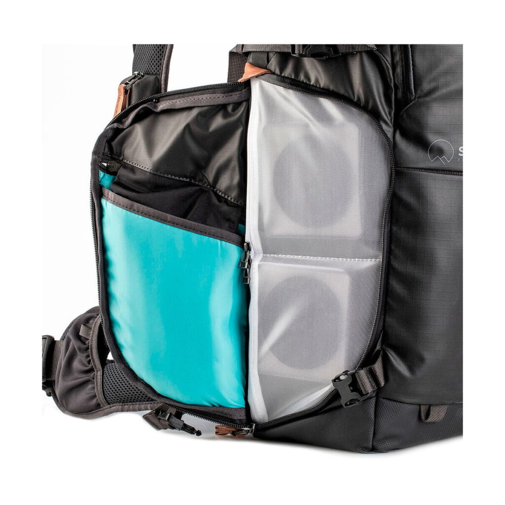 Shimoda_Designs_Explore_v2_30-Musta_008 Lähikuva Shimoda Designs Explore v2 30 -kamerareppu, musta sivutasku näyttää järjestetyt lokerot, joissa on sininen insertti, vetoketjullinen verkko-osio ja kaksi sylinterimäistä esinettä sisällä.