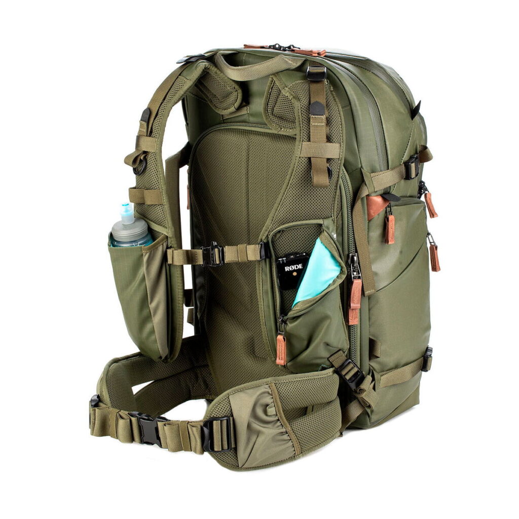 Shimoda Designs Explore v2 30 -kamerareppu, vihreä, on oliivinvihreä reppu, jossa on pehmustetut hihnat, useita vetoketjullisia lokeroita, sivutaskut vesipullolle, puhelimelle ja maskille sekä tuulettuva selkäpaneeli ja tukeva vyötärövyö.