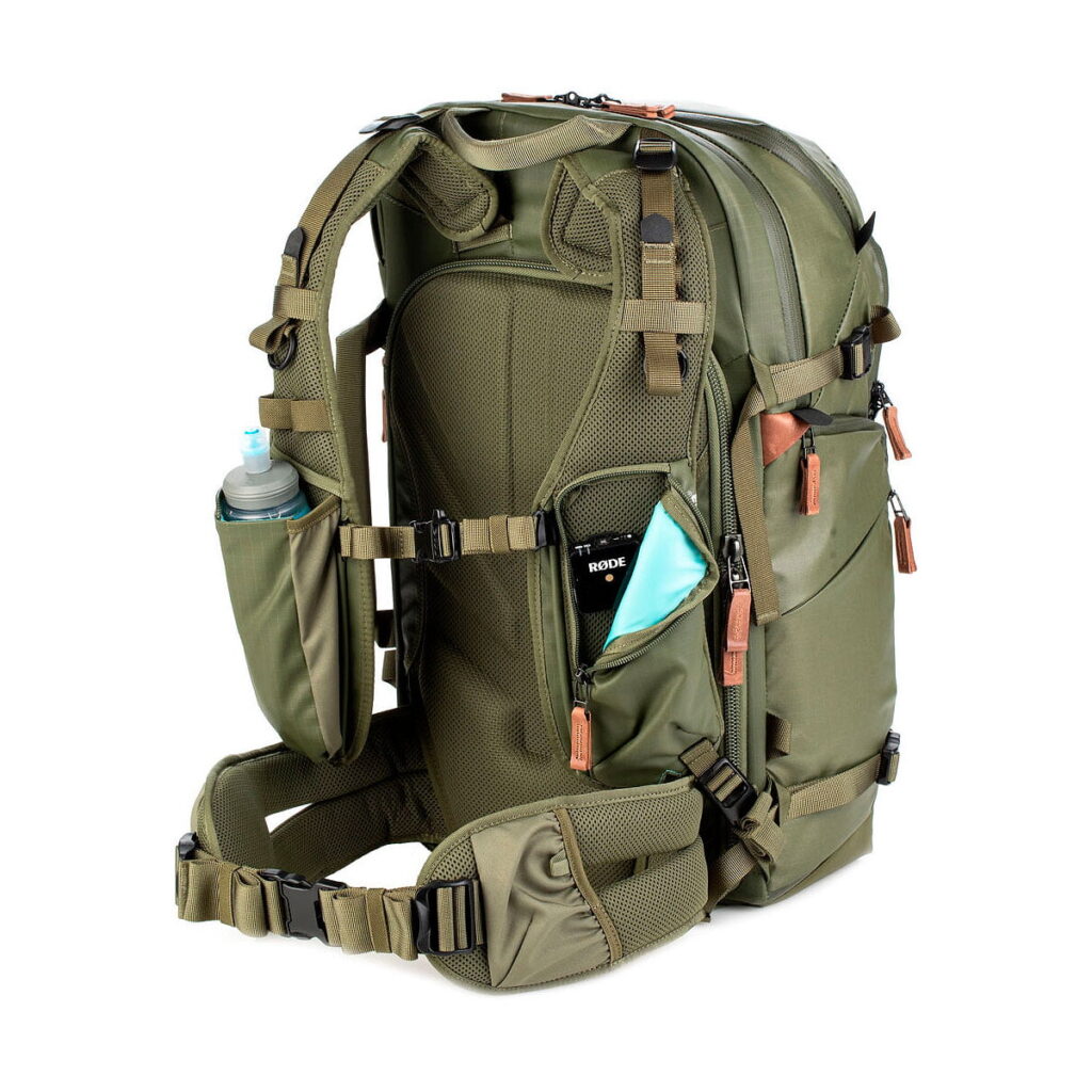 Vihreässä Shimoda Designs Explore v2 35 -kamerareppussa on useita lokeroita, säädettävät pehmustetut hihnat, vyötäröhihna ja vesipullonpidike sivulla. Vesipullo, kartta ja muistikirja löytyvät sen taskuista.