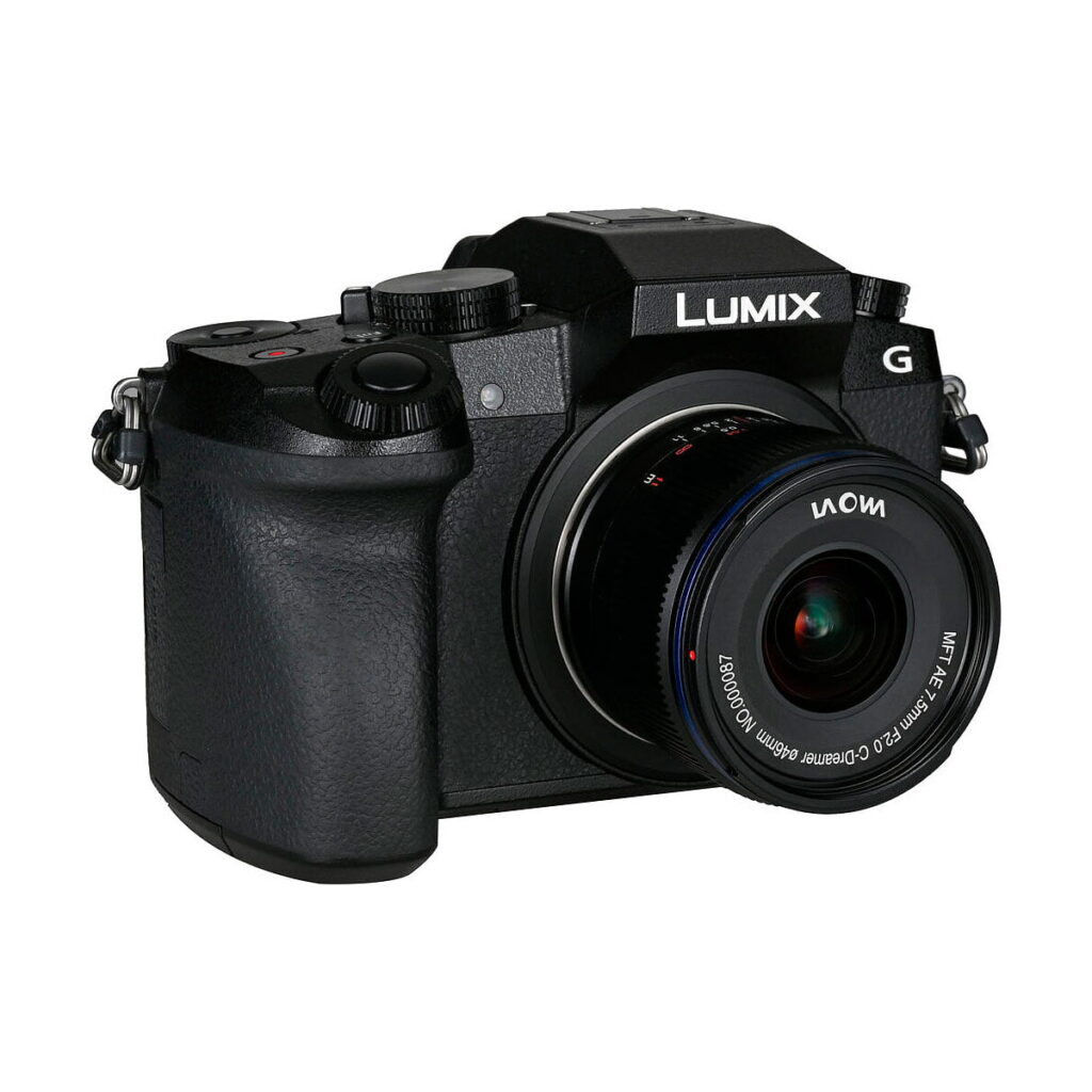 Laowa_7_5mm_f_2_MFT_Auto_Aperture_Version_010 Musta Panasonic Lumix G -peilitön digitaalikamera, johon on kiinnitetty Laowa 7,5 mm f/2 MFT AE -objektiivi, kuvattuna pienessä kulmassa valkoisella taustalla.