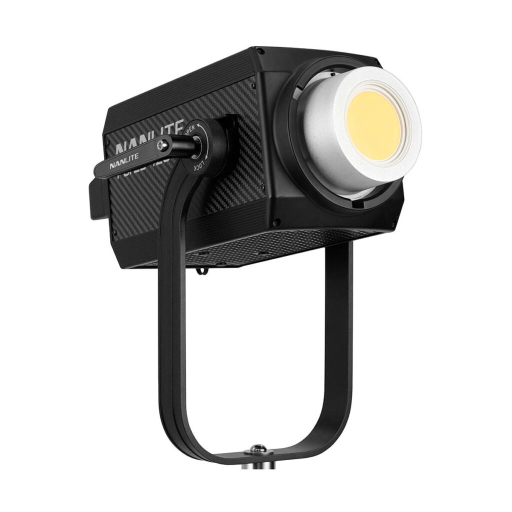 NANLITE_Forza_720_LED_Spotlight_003 NANLITE Forza 720 LED Monolight on musta, laatikon muotoinen studiovalaisin, jossa on hopeinen ja keltainen linssi, joka on asennettu U-muotoiseen kiinnikkeeseen, jossa on säätönupit, ja joka on esitetty valkoisella pohjalla.