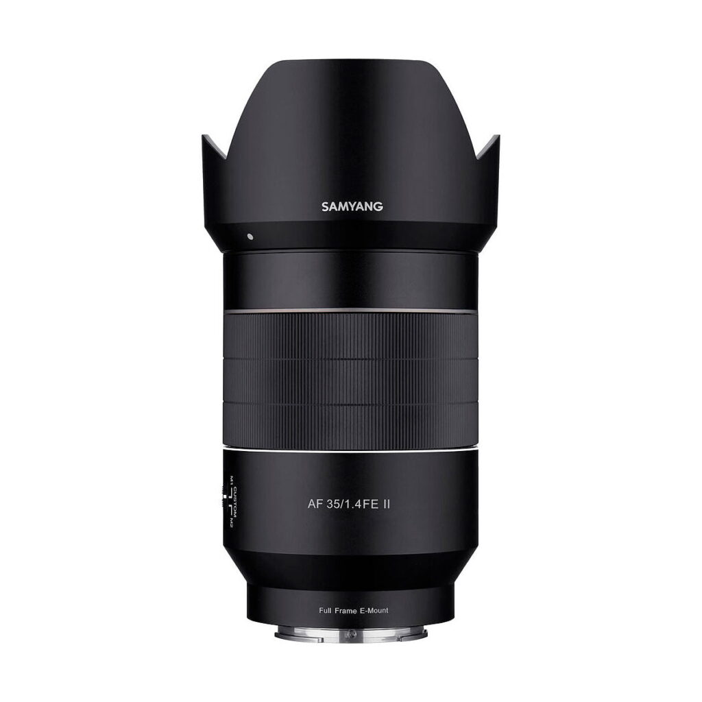 Samyang_35mm_f_1_4_AF_II_001 Lähikuva mustasta Samyang AF 35mm f/1.4 II - Sony E -objektiivista, jossa on vastavalosuoja, valkoiset merkinnät ja moderni muotoilu, valkoista taustaa vasten.