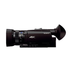 Sony_FDR-AX700_004 Mustan Sony FDR-AX700 4K -videokameran sivukuva, jossa on suuri objektiivi, ohjauspainikkeet ja näkyvä okulaari valkoista taustaa vasten.