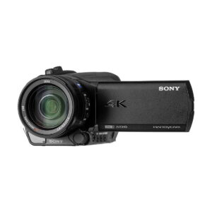 Sony_FDR-AX700_008 Kuvassa on musta Sony FDR-AX700 4K -videokamera, jossa on Zeiss-objektiivi, avoin LCD-näyttö ja useita sivupainikkeita.