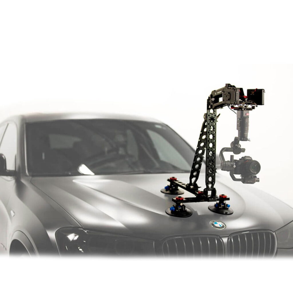 Tilta_Hydra_Alien_Car_Mounting_System_V-Mount_6 Tilta Hydra Alien Car Mounting System (V-Mount) on kiinnitetty harmaan BMW:n konepeltiin, mikä mahdollistaa vakaan kuvaamisen ajoneuvosta käsin. Tausta näyttää enimmäkseen valkoiselta ja epäselvältä.