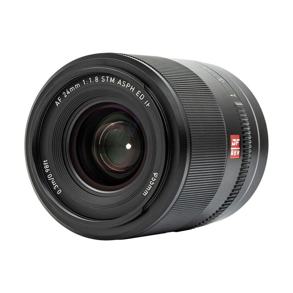 Viltrox_AF_24mm_f_1_8-Nikon_Z_003 Lähikuvassa Viltrox AF 24mm f/1.8 -objektiivi, Nikon Z näkyy sen musta runko, eturengas, jossa on AF 24mm 1:1.8 STM ASPH ED IF -merkinnät, näkyvät lasielementit ja kuvioitu tarkennusrengas.