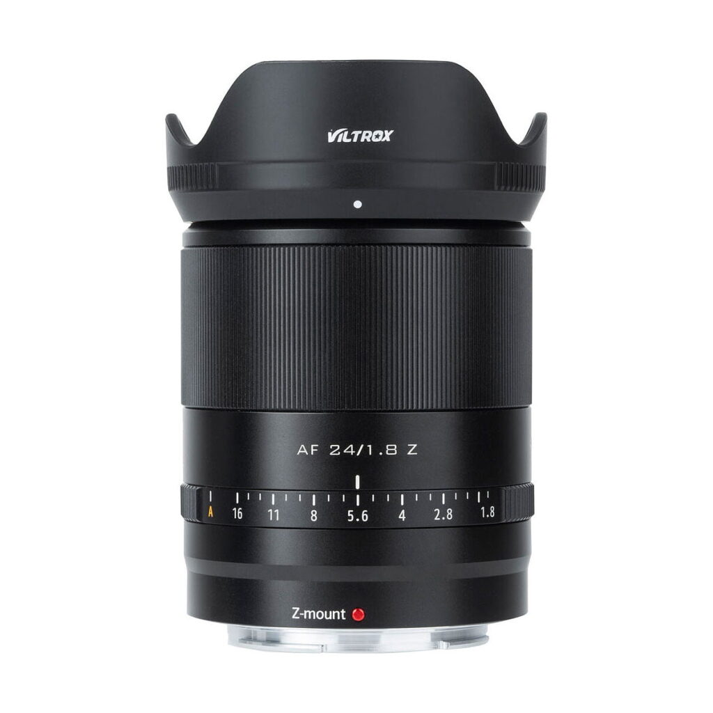 Viltrox_AF_24mm_f_1_8-Nikon_Z_009 Viltrox AF 24mm f/1.8 -objektiivi, Nikon Z, jossa on musta runko, uurrettu tarkennusrengas, aukkomerkinnät ja terälehden muotoinen vastavalosuoja, näkyy pystyssä valkoista taustaa vasten.