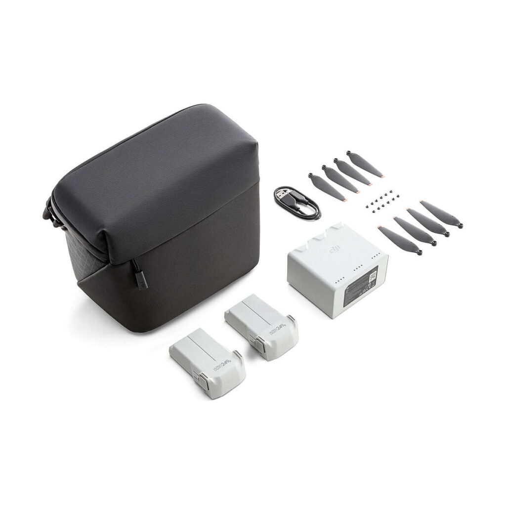 DJI_Mini_3_Pro_Fly_More_Kit_002 DJI Mini 3 Pro Fly More Kit sisältää mustan kantolaukun, kaksi harmaata akkua, latauskeskittimen, USB-kaapelin, kuusi potkuria ja pieniä ruuveja - kaikki valkoisella pohjalla.