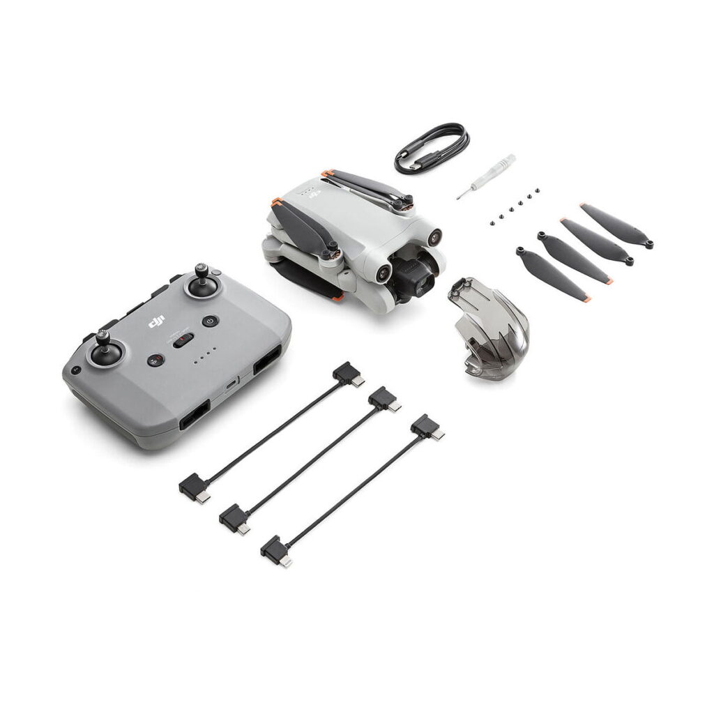 DJi_Mini_3_Pro_000 DJI Mini 3 Pro + RC-N1 Ohjain -pakkaus sisältää taitetun lennokin, kauko-ohjaimen, akkulaturin, ylimääräiset potkurit, ruuvit, ruuvimeisselin, kolme USB-kaapelia ja kaapelin, jotka on järjestetty siististi valkoiselle taustalle.