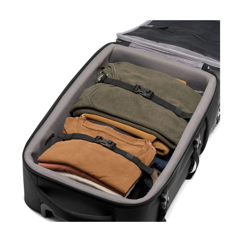 Manfrotto_Rolling_Bag_Advanced_III_006 Manfrotto Rolling Bag Advanced III näkyy avattuna, siististi pakattuna maanvärisillä vaatteilla, jotka on kiinnitetty kahdella säädettävällä hihnalla.