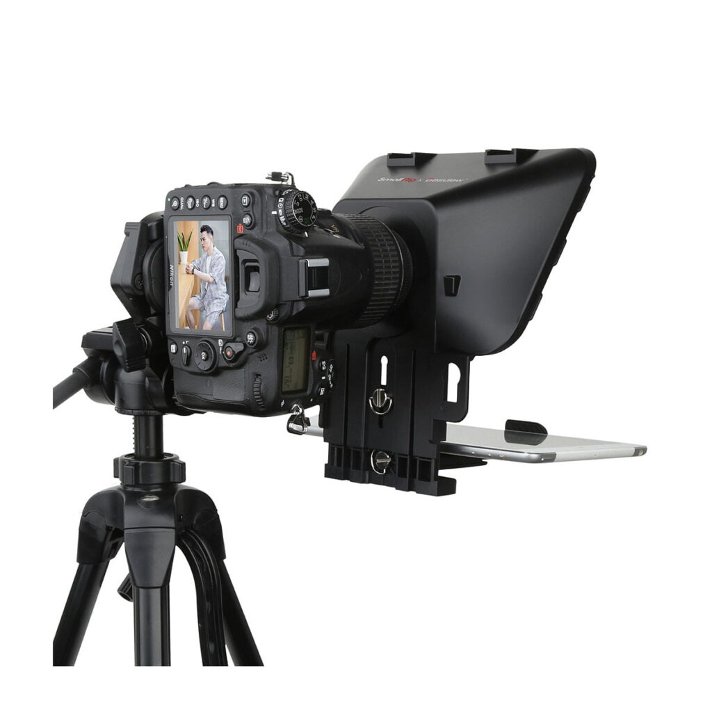 SmallRig_3374_Portable_Tablet_Smartphone_DSLR_Teleprompteri_010 SmallRig 3374 Portable Tablet/Smartphone/DSLR Teleprompter pitää jalustalla olevaa DSLR-kameraa ja älypuhelinta. Kameran näytöllä näkyy istuva, puhuva henkilö, kun teleprompteriasetelma on suunnattu eteenpäin.