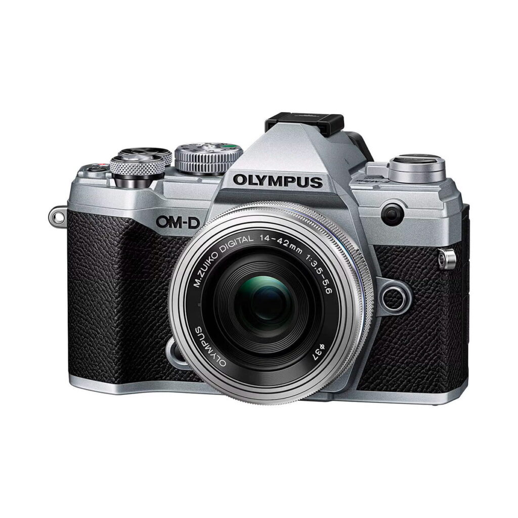 olympus_e-m5iii_14-42ez_hopea Olympus OM-D E-M5 MK III hopean ja mustan värisessä Olympus OM-D E-M5 MK III -kamerassa on 14-42mm f/3.5-5.6 EZ-objektiivi, jossa on kuvioitu kahva ja useita yläreunan säätöpyöriä helppoa hallintaa varten.