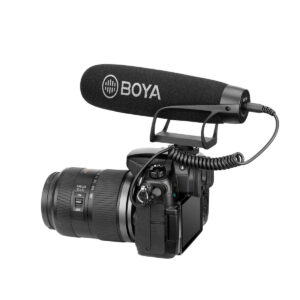 Boya-BY-BM2021-2 Zoom-objektiivilla varustetun digitaalikameran päälle on asennettu suuri Boya BY-BM2021 3,5 mm:n haulikko-kondensaattorimikrofoni, joka on yhdistetty kelattuun äänikaapeliin, eristettynä valkoiselle taustalle.