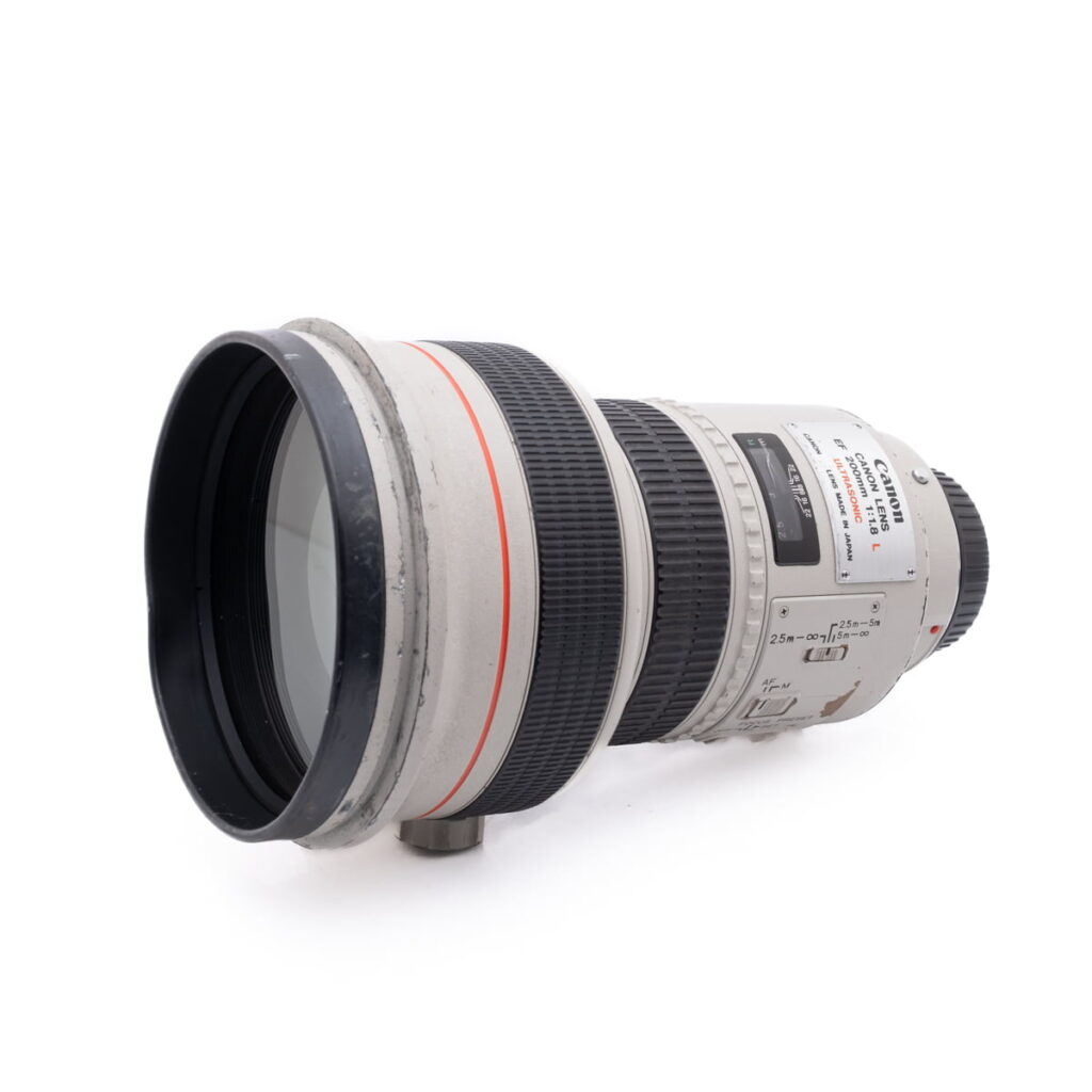 Canon 200mm f1.8L-2 Käytetty Olympus OM-D E-M1X (SC 460) -kamera on kuvassa hieman vasemmalle suunnattuna valkoista taustaa vasten.