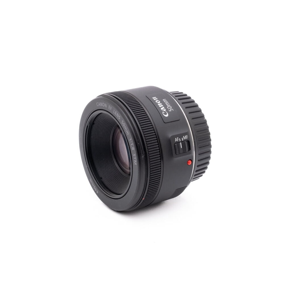 Canon EOS M50 - Käytetty kamera näkyy valkoisella pohjalla, ja sen objektiivilasi, ohjauskytkin ja objektiivin kiinnitys on kuvakulmassa.
