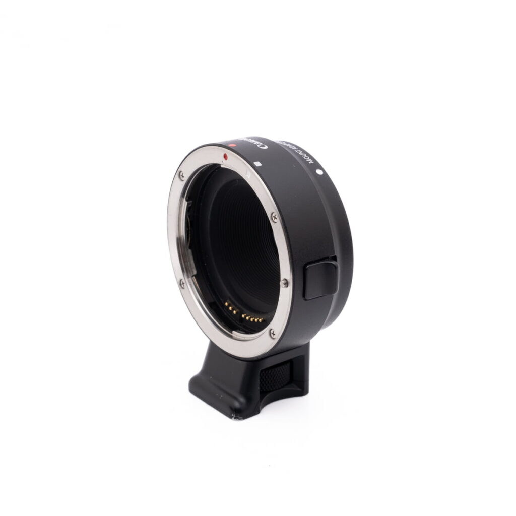 Canon EF-EOSM adapter-2 Musta Canon EOS M50 -objektiivin kiinnityssovitin, jossa on metallirengas ja elektroniset koskettimet, seisoo pystyssä valkoisella taustalla.