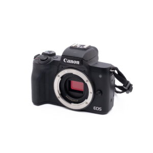 Canon M50-2 Musta Canon EOS M50 - Käytetty peilitön kamerarunko ilman objektiivia, jossa näkyy kenno ja objektiivin kiinnitys, sekä kiinnitetty käsihihna valkoisella taustalla.