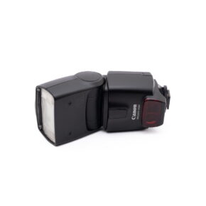 Canon Speedelite 430ex-1 Musta Canon Speedlite 430EX - Käytetty -kamerasalama lepää valkoisella pohjalla vasemmalle kallistettuna, ja sen rungossa näkyy Canon-logo ja mallinimi.