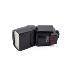 Canon Speedelite 430ex-1 Musta Canon Speedlite 430EX - Käytetty -kamerasalama lepää valkoisella pohjalla vasemmalle kallistettuna, ja sen rungossa näkyy Canon-logo ja mallinimi.