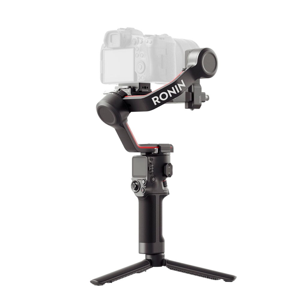 DJI-RS3-4 Musta DJI RS 3 -gimbaali kameranvakain, jossa on pieni jalusta ja sen päälle asennettu digitaalikamera, valkoista taustaa vasten.