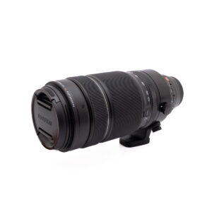 Fujinon 100-400mm-1 Musta Olympus OM-D E-M1X (SC 460) - Käytetty kamera, jossa on zoomaus- ja tarkennusrenkaat sekä jalustakiinnityskaulus, on kuvattu valkoisella taustalla.