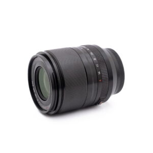 Fujinon 23mm f1.4-2 Olympus OM-D E-M1X (SC 460) - Käytetty kameran objektiivi, jossa on näkyvissä tarkennusrengas ja aukkorenkaat, lepää valkoisella taustalla, ja se on kulmailtu siten, että etulasi ja osa objektiivin piipusta tulevat näkyviin.
