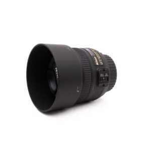 Nikon Nikkor Z DX 16-50mm f/3.5-6.3 VR - Käytetty objektiivi, johon on kiinnitetty vastavalosuoja, näkyy valkoisella taustalla vinossa, ja siinä näkyvät tarkennuksen ja kytkimen säätimet.