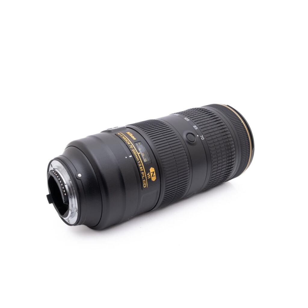 Nikkor 70-200mm f2.8-3 Käytetty Canon Speedlite 430EX, jossa on musta runko ja valkoiset merkinnät, lepää kyljellään valkoista taustaa vasten, ja sen kiinnitys ja ohjauspaneeli näkyvät.