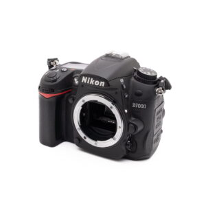 Nikon D7000-2 Musta Nikon D7000 (SC 7000) - Käytetty DSLR-kameran runko näkyy valkoisella taustalla, ja sen objektiivin kiinnitys on näkyvissä, ja sen sivussa ja yläreunassa on erilaisia ohjauspainikkeita ja säätimiä.
