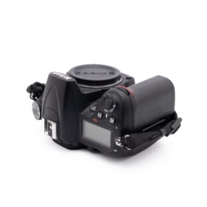 Nikon D7000-4 Nikon D7000 (SC 7000) - Käytetty digitaalikameran runko, jossa on Sigma-objektiivin suojus, näyttö, ohjauspainikkeet ja musta hihna valkoisella pohjalla.