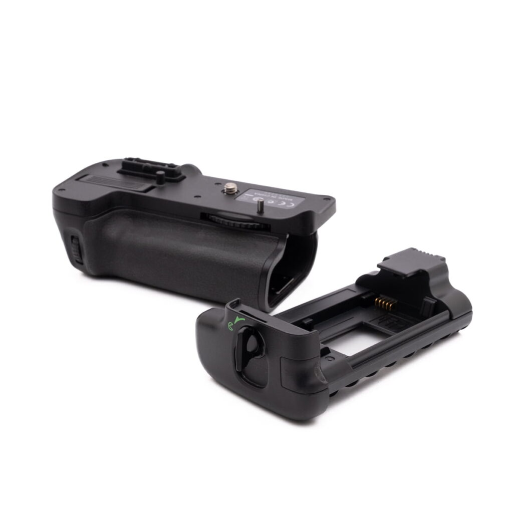 Nikon MB-D11-4 Kaksi Nikon MB-D11 akkukahvaa - Käytetty kahva on valkoisella pohjalla - yksi litteä, toinen pystyasennossa - ja siinä näkyvät säätimet, valitsimet ja akkulokerot.