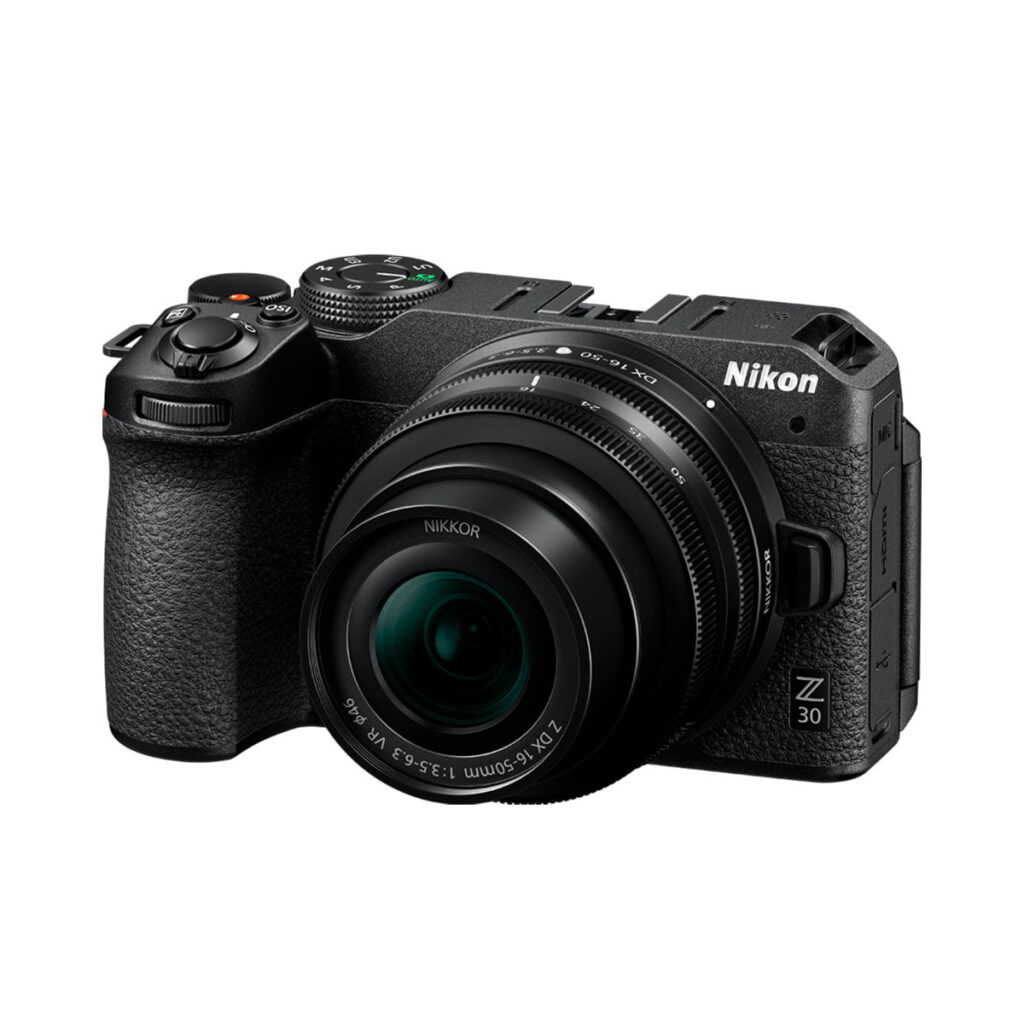 Nikon-Z30-2 A Nikon Z30 -järjestelmäkamera musta runko irrotettavalla objektiivilla, esitelty kulmasta valkoisella taustalla; kamerassa on teksturoitu ote ja näkyvät säätöpainikkeet.