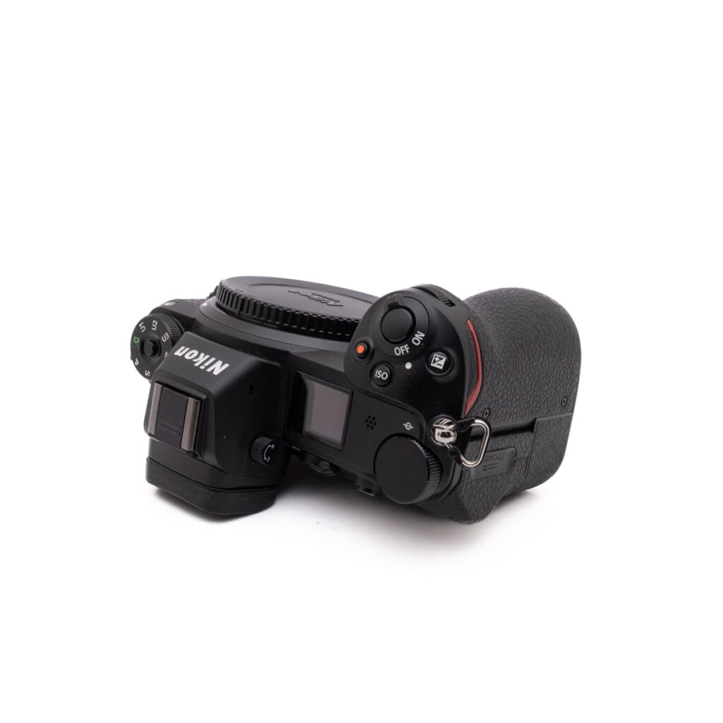 Nikon Z6-4 Sigma 30mm f/1.4 DC DN Sony E -objektiivi (käytetty) ylhäältä kuvattuna kulmasta, jossa näkyy objektiivin tynnyri, tarkennusrengas ja kiinnitys. Objektiivin suojus on kiinnitetty, ja tausta on pelkkä valkoinen.