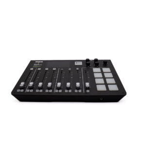 RodeCaster pro RodeCaster Pro (Kunto K5, Takuu 6kk) - Käytetty on musta äänimikseri, jonka yläpinnalla on useita liukusäätimiä, painikkeita, nuppineuvoja ja neliönmuotoisia padeja valkoisella pohjalla.